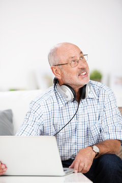 älterer mann mit kopfhörern und laptop