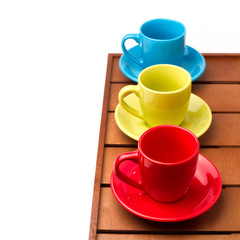 Colorful cups on wooden tabletop over white background