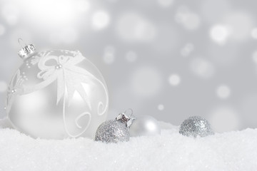 Silver Christmas ornaments in snow with twinkling lights