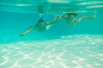 loving couple hugs, kisses and swims underwater in the pool under the open sky