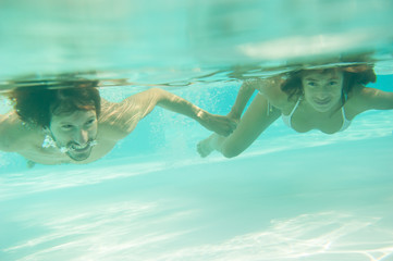 loving couple hugs, kisses and swims underwater in the pool under the open sky