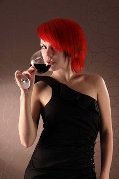 Schlanke rothaarige Frau trinkt Rotwein
