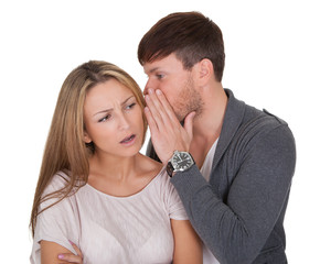 Man whispering in a woman's ear