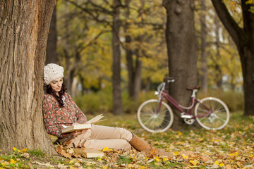 Young woman reading ni the autumn forest