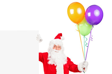 Happy Santa claus standing next to a billboard and holding ballo