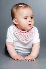 Cute baby girl against grey background. Studio shot.