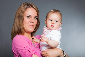 Happy young mother in love with her baby daughter. Studio shot.