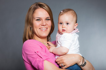 Happy young mother in love with her baby daughter. Studio shot.