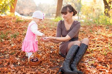 Family cute little girl and cheerful mom In a park autumn