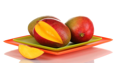 Ripe appetizing mango on red plate isolated on white