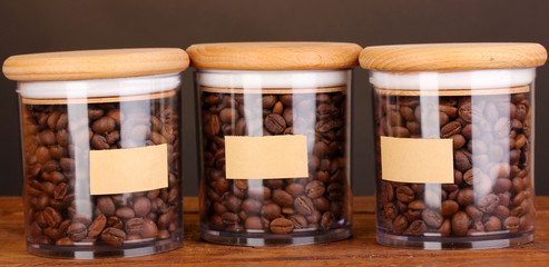 Coffee beans in jars on table on brown background