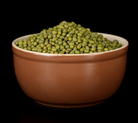 Mung beans in brown bowl isolated on black