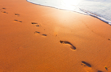 Fototapeta na wymiar plaża, fala, a kroki w czasie zachodu słońca