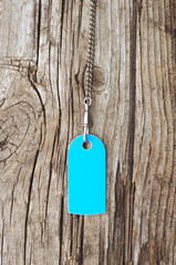 blank blue tag on with silver chain old wooden background