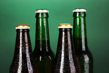 Coloured glass beer bottles on green background