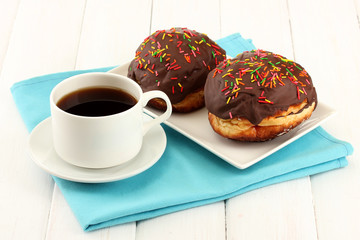 Tasty donuts on color plate on light wooden background