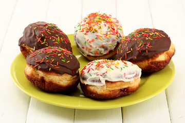Tasty donuts on color plate on light wooden background