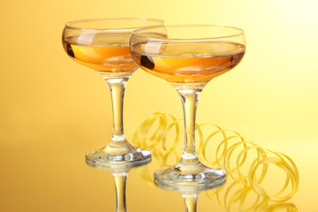 glasses of champagne and streamer on yellow background