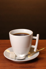 Coffee cup on wooden table on brown background