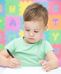 Little boy is writing on his copybook