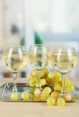 White wine in glass on salver on room background