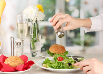 Female hand with  dinner on bright background