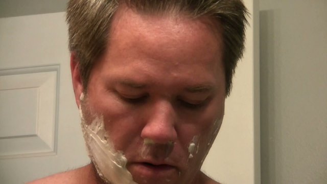 Man Shaving Face in Mirror
