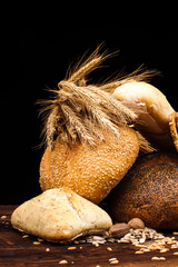 assortment of baked bread on wooden table and black background