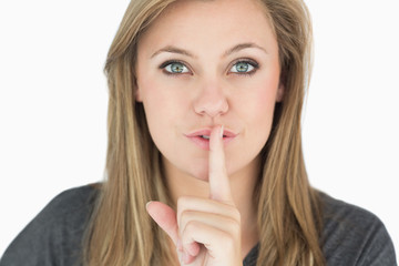 Naklejka premium Blond woman putting finger on mouth