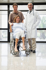 Obraz premium Pregnant woman in wheelchair, partner and doctor smiling