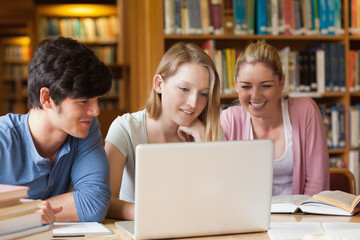 Fototapeta na wymiar Uczniowie siedzą w bibliotece z laptopem