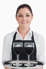 Smiling waitress holding two glasses of wine