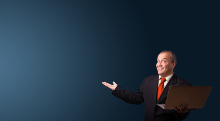 businessman holding a laptop and presenting copy space