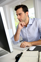 Fototapeta premium Portrait of young office worker sitting at desk