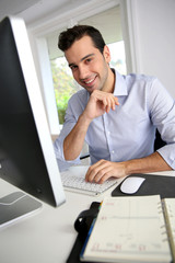 Fototapeta premium Portrait of young office worker sitting at desk