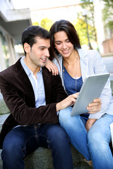 Young couple websurfing on internet with tablet in town