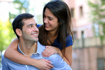 Cheerful young man carrying girlfriend on his back