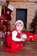 Beautiful blond little girl in a red Christmas hat, gifts