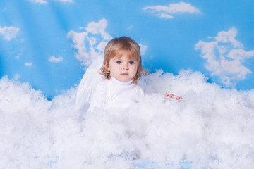 Baby with angel wings sitting in the clouds