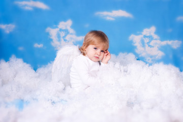 Baby with angel wings sitting in the clouds