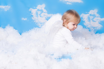 Baby with angel wings sitting in the clouds