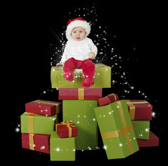 baby seated on a stack of christmas presents