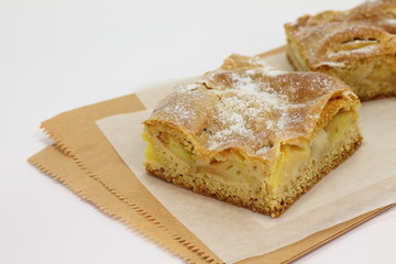 Slice of an apple pie on a baking paper