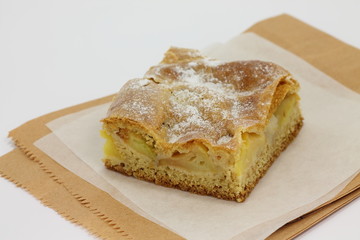 Slice of an apple pie on a baking paper