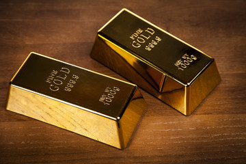 Two gold bars on wooden table