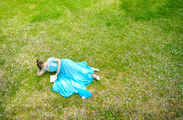 Young girl lying with book on the grass