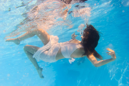 Woman in a white dress underwater in swimming pool