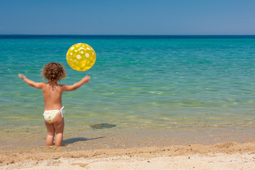 Naklejka na ściany i meble little girl playing with a ball on the beach