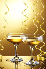 glasses of champagne and streamer on yellow background