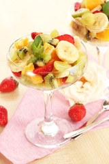 Fresh fruits salad and strawberries on wooden table